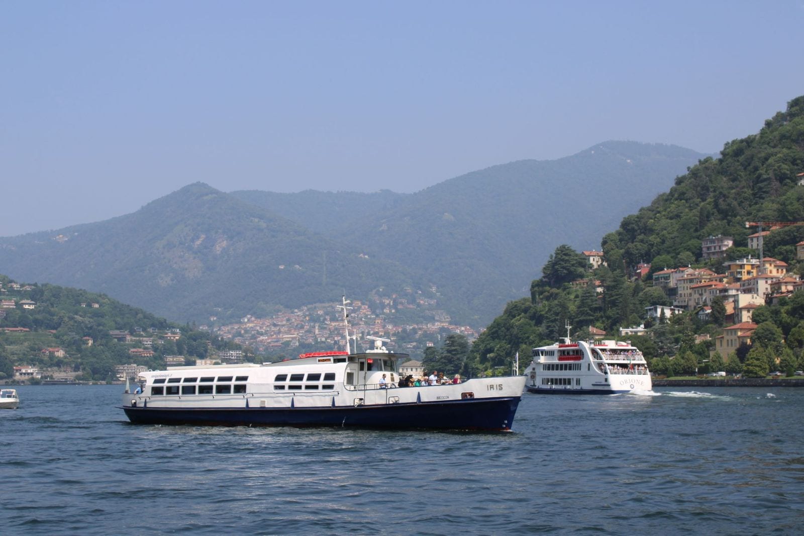 Bateaux de passagers sur le lac de Côme devant des collines boisées
